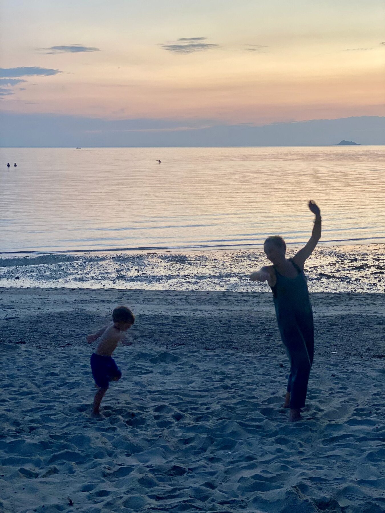 An adult and child dancing together on the beach